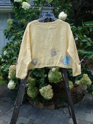 1999 Weathervane Jacket Crown Buttercup Size 2 displayed on a wooden ladder, showcasing unique front mix-match buttons, top porcelain button, inward rounded side hem, deeper V neckline, and summer tulip theme paint.