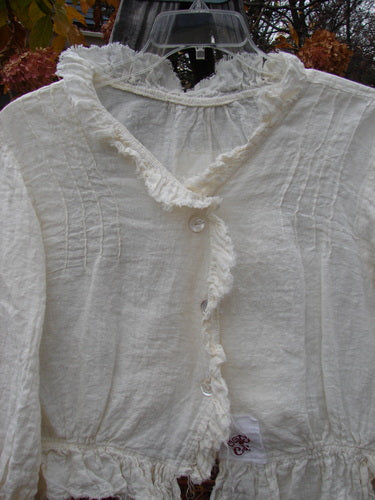 Magnolia Pearl Homespun Linen Raglan Tab Jacket Farm Love Off White OSFA displayed on a hanger, showcasing its ruffled V neckline, frayed hem, and pearl button accents.