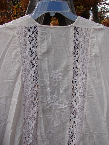 Magnolia Pearl European Cotton Embroidered Lace Duster in Antique White, OSFA: Open flowing front, cap drop sleeves, gathered vertical lace seams, matching lace hem, embroidered floral vine backdrop. Bust 66, waist 66, hips 66, sweep 70, front back length 46, sides 50 inches.