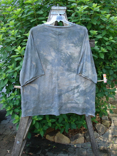 Barclay Raw Edge Flutter Collar High Low Top on a hanger, showcasing its rounded batiste flutter neckline, short dolman sleeves, boxy shape, and distinctive high-low raw edge hemline.