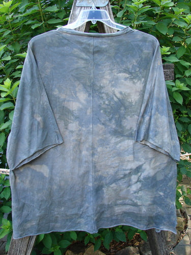 Barclay Raw Edge Flutter Collar High Low Top Blue Fish Love Mottled Steel OSFA hangs on a clothesline, showcasing its distinctive raw edge dolman sleeves and wide boxy shape with a hi-low hemline.