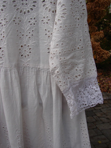 Magnolia Pearl European Cotton Eyelet Lucienne Dress, antique white, close-up of lace and eyelet fabric, rounded lacey neckline, three-quarter length sleeves, lace seamed bodice and full skirt, gathered waist seam, generous lace lower sleeves.