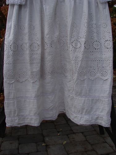 A white lace curtain on a clothesline, close-up of a white dress, and a close-up of a bed. Magnolia Pearl European Cotton Eyelet Lucienne Dress in Antique White.