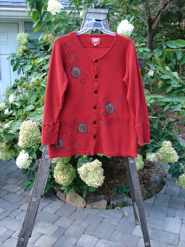 2000 Thermal Lu Top Pinwheel Bittersweet Size 2 displayed on a swing, featuring ribbed cuffs and rubberized buttons with a slightly A-line shape and lightweight thermal fabric.