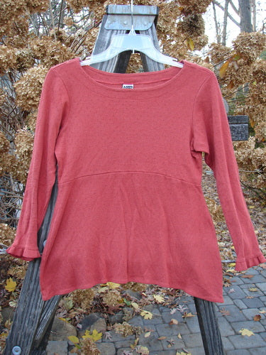 2000 Wool Pointelle Anais Top Unpainted Bittersweet Tiny Size 1: A red shirt on a swinger with unique features like lettuce edging, empire waist seam, tailored waistline, and narrow lower sleeves.