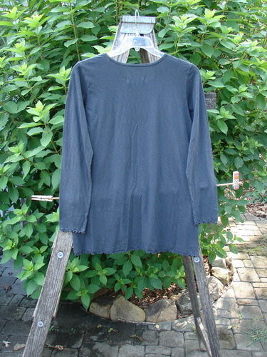 Barclay NWT Modal Batiste Layer Top Unpainted Shadow Size 1, featuring long sleeves and a rounded neckline, displayed on a wooden rack, highlighting its A-line shape and raw edge details.