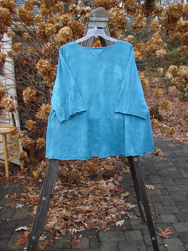 A blue shirt on a clothes swinger, part of the Barclay Three Quarter Sleeved A Lined Tee collection in Mottled Aqua Dust, size 2.