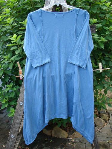 Barclay NWT Wildflower Tunic Garden Blend Blue Bird Size 0 displayed on a clothes rack, showcasing its flutter hemline, raw-edged front panel, and exterior drop front pockets, emphasizing unique design elements.