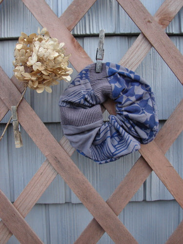 Barclay PMU Cotton Lycra & Thermal Hair Scrunchie Diamond Grid Brum Extra Large, displayed draped over a wooden fence, showcasing its ruffled texture and elastic band, celebrating sustainable vintage design.