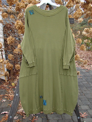 A Barclay Patched Thermal Curve Dress in Greenroot, size 1, on a clothes rack. Unique figure eight shape, thicker rib neckline, exterior stitchery, and double rib top exterior pockets. Features three sweet signature painted patches. Bust 50, waist 52, hips 54, length 50 inches.