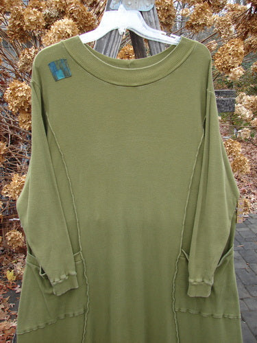A Barclay Patched Thermal Curve Dress in Greenroot, Size 1, on a clothes rack. Unique figure eight shape, thicker rib neckline, exterior stitchery, and double rib top exterior pockets. Features three sweet signature painted patches. Made from mid-weight cotton thermal. Bust 50, waist 52, hips 54, length 50 inches.