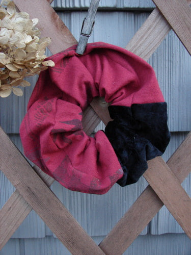 Barclay PMU Organic Cotton & Velvet Hair Scrunchie Vine Grid Black Red Extra Large displayed draped over a wooden fence, showcasing its ruffled texture and elastic band, emphasizing its vintage-inspired design.