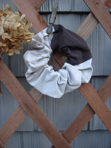 Barclay PMU Cotton & Lycra Hair Scrunchie Letter Brown Fawn Extra Large displayed on a wooden fence, showcasing its ruffled texture, thin elastic band, and vintage-inspired capital letter design.