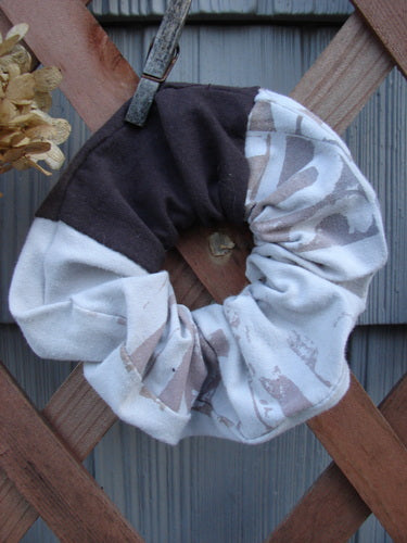 Barclay PMU Cotton & Lycra Hair Scrunchie Letter Brown Fawn Extra Large displayed on a wooden fence, showcasing its ruffled fabric and elastic band, embodying sustainable vintage design from Bluefishfinder.com.