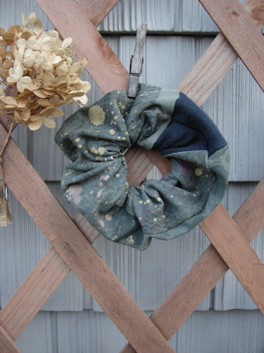 Barclay PMU Cotton Lycra & Thermal Hair Scrunchie Rain Pond Green Extra Large displayed on a wooden fence, showcasing its ruffled texture and elastic band, exemplifying sustainable vintage design from Bluefishfinder.com.