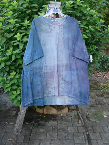 Barclay NWT Art Tee Celestial Mottled Purple Blues OSFA displayed on a wooden stand, highlighting its tunic length, drop shoulders, loose three-quarter sleeves, and varying hemline.