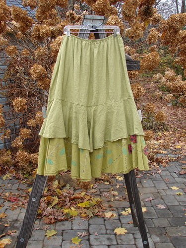 Barclay Linen Two Tier Ruffle Skirt Ladybug Yellow Olive Size 2: A medium weight linen skirt with a double-layered design. Features a thin elastic waistline, wide spinning fall, and a huge lower batiste ruffle painted with tiny leaf motifs. Perfect for layering or wearing alone. Waist: 38-48, Hips: 58, Hem Circumference: 90, Upper Linen Length: 27, Lower Batiste Length: 34.