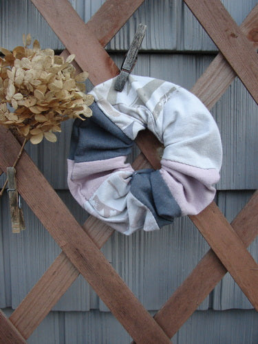 Barclay PMU Cotton & Lycra Hair Scrunchie Letter Brown Fawn Pink Extra Large displayed on a wooden fence, showcasing its ruffled fabric and elastic band, emphasizing the sustainable vintage style.