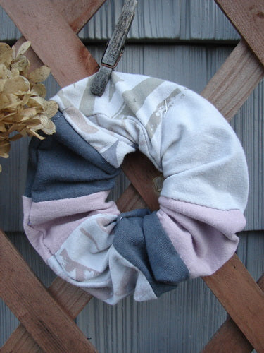 Barclay PMU Cotton & Lycra Hair Scrunchie Letter Brown Fawn Pink Extra Large, showcased on a wooden fence, highlights its ruffled texture and the distinct capital letter theme design.