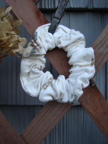 1994 PMU Cotton Button Hair Scrunchie Floral Tea Dye Large displayed on a wooden surface, highlighting its ruffled fabric and elastic band, embodying vintage style from Bluefishfinder.com's sustainable collection.