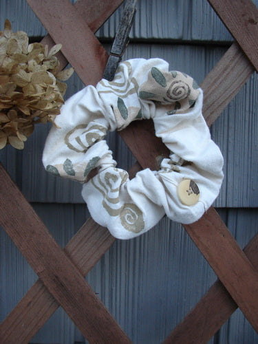 1994 PMU Cotton Button Hair Scrunchie Floral Tea Dye Small on wooden fence, showcasing ruffled fabric, floral theme, and elastic interior band, highlighting Bluefishfinder.com's vintage and sustainable fashion ethos.