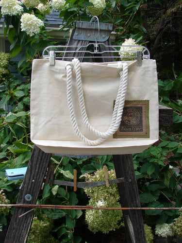 1998 PMU Patched Canvas Rope Tote Bag Hydrangea Leaf Natural OSFA displayed on a wooden rack, featuring cotton rope shoulder straps, a generous top opening, and Blue Fish's signature patch on the rear.