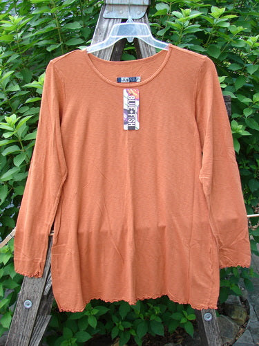 Barclay NWT Modal Slub Layer Top Unpainted Ember Size 0 displayed on a clothes rack, featuring long narrow sleeves, A-line shape, raw edges, and a rounded neckline, ideal for layering.