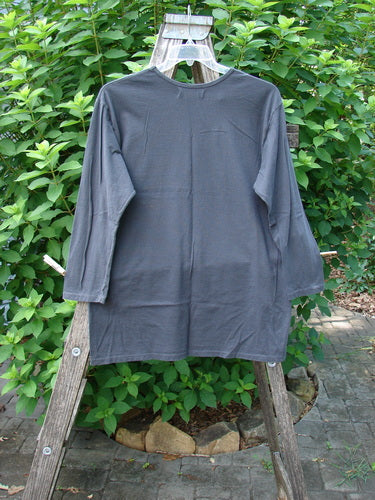Barclay NWT Long Sleeved Studio Tee Metallic Forest Life Shadow Size 0 hangs on a wooden rack, showcasing its straighter shape, rounded neckline, and artistic metallic forest life theme design, perfect for spring.