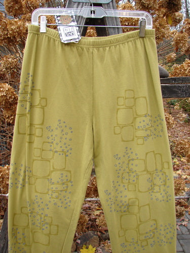 A pair of Barclay NWT Cotton Lycra relaxed leggings hanging on a clothesline, showcasing the Star Path Green Olive design.