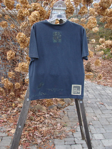 1999 Short Sleeved Tee Celtic Clock Black Size 1: Blue t-shirt with a Celtic clock theme paint and Blue Fish patch. Straight shape, rolled ribbed neckline. Made of organic cotton jersey.