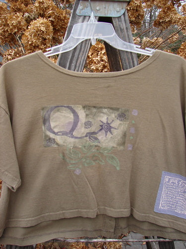 1994 Song Top Garden Bark Size 1: A brown shirt with a logo on it. Wide boxy shape, shallow neckline, vintage buttons, and a painted breast pocket.