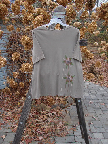 Barclay Short Sleeved A Line Top Lolly Daisy Storm Grey Size 0: A t-shirt with a flower design on it, displayed on a wooden rack.