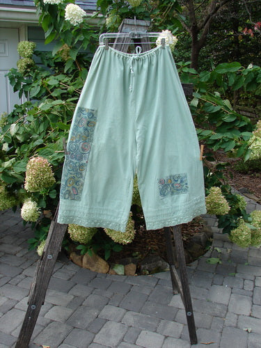 1992 PMU Patched Pantaloon Continuous Spin Cucumber OSFA hanging on a clothesline, showcasing wide legs, drawcord waist, antique lace trim, and signature Blue Fish patches.