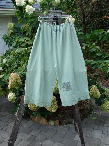 1992 PMU Patched Pantaloon Continuous Spin Cucumber OSFA displayed on a clothes rack, featuring antique lace trims, a drawcord waistline, and signature patches, embodying vintage Blue Fish clothing's unique style.