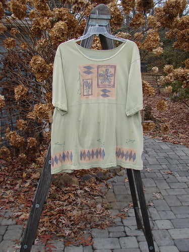 Image alt text: "1993 3 Square Dress with trinket and diamond theme, featuring a green shirt with a pattern, a picture, and floral and diamond drawings on a cloth stand."