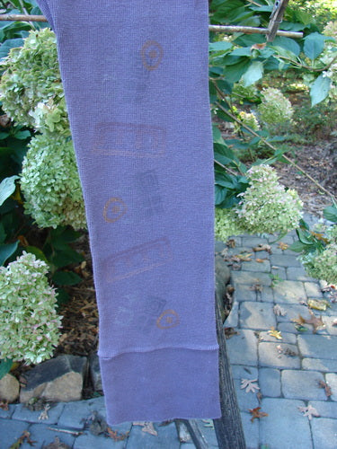 The 2000 Thermal Layering Lu Pant Soft Geo Eggplant Size 1 displayed with ribbed lowers and pocketless hips, showcasing its professionally replaced elastic waistband against a natural outdoor setting.