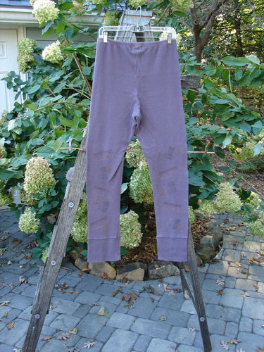 2000 Thermal Layering Lu Pant Soft Geo Eggplant Size 1 hanging on a clothesline, showcasing ribbed lowers and a pocketless hip design against a natural outdoor backdrop.