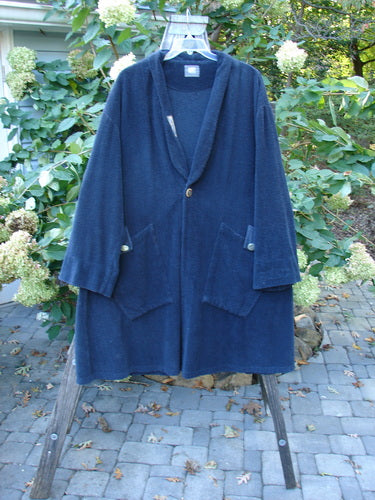 1999 Patched Chenille Angle Pocket Jacket, featuring oversized vintage button closures, diagonal floppy pockets, and a unique holiday-themed patch, displayed on a swing with a blurred background and foliage.