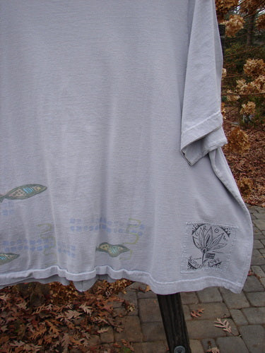 1999 Tiny Pocket Top Fish Water Size 2: A white shirt with fish design on a pole. Features include a swingy cropped A-line shape, front oval pockets, and a ceramic button. Perfect for fisher gals!