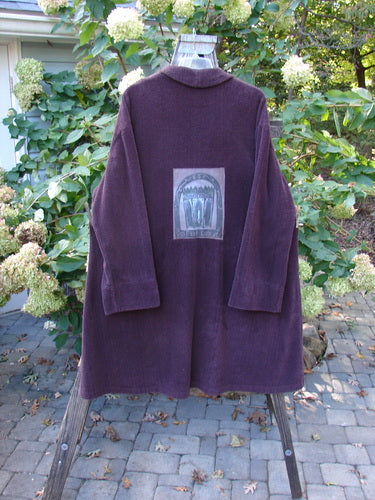 1999 Patched Chenille Angle Pocket Jacket in Deep Burgundy displayed on a wooden stand, showcasing oversized vintage buttons, diagonal front pockets, and a unique vintage design from the Holiday Winter Collection.