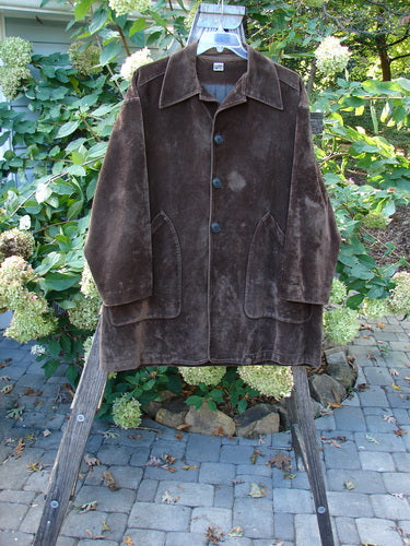 1999 Limited Edition Shed Jacket Unpainted Deepest Brown Size 1 on a wooden stand, showcasing its A-line shape, rubberized buttons, and oversized angular pockets, embodying a vintage, sophisticated style.