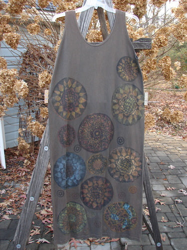 Image alt text: Sleeveless grey dress with metallic pinwheel design on a wooden ladder.