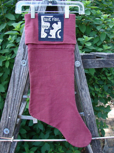 1995 Reprocessed Holiday Stocking Festive Hollyberry OSFA displayed on a ladder, featuring striking blue fish paint, a bright signature patch, and a sweet hang tab for festive gifting.