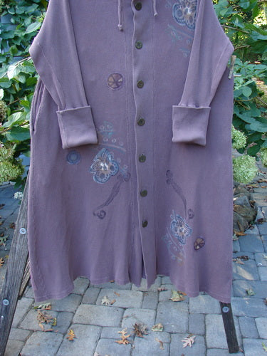 The 1995 PMU Thermal West Wind Coat Hooded Butterfly Currant Size 1 hanging outdoors, showcasing its oversized hood, ribbed accents, deep pockets, and unique butterfly and pinwheel patches.