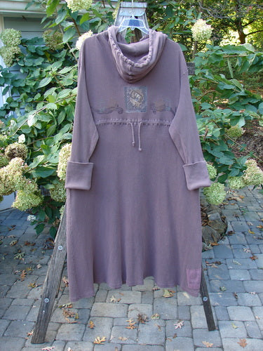 1995 PMU Thermal West Wind Coat Hooded Butterfly Currant Size 1 displayed on a wooden rack, showcasing its oversized hood, deep pockets, and unique butterfly patches, capturing its vintage charm and flowing design.