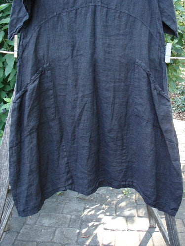 Barclay NWT Linen Cross Over Serenade Urchin Dress Unpainted Black Size 0, displayed hanging, features a unique crossover neckline, empire waist, and varying hemline, accentuating its artisan design.