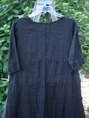 Barclay NWT Linen Cross Over Serenade Urchin Dress in Unpainted Black, Size 0, featuring a unique one-sided crossover neckline, empire waist, and double exterior side pockets, hanging outdoors.