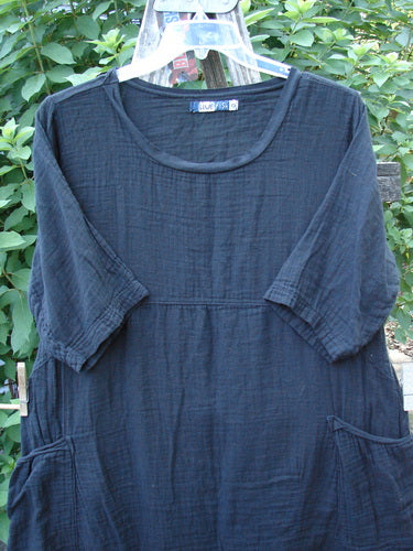 Barclay NWT Gauze Seaside Tunic Dress Unpainted Black Size 0 displayed on a clothes rack showcasing its flutter neckline, wide short sleeves, and unique hemline, emphasizing its airy cotton gauze fabric.