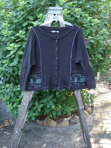Barclay Thermal Exterior Stitch Two Pocket Jacket Geos Black Size 0 displayed on a wooden rack, highlighting its rounded neckline, long narrowing sleeves, full button front, and double drop exterior painted pockets.