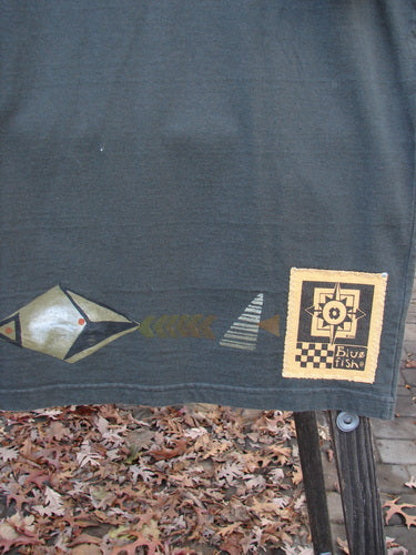 Image alt text: 1998 Short Sleeved Tee Diamond Game Domino Size 1: A cloth with a design of black and white envelopes, a logo, a fence, and brown leaves.